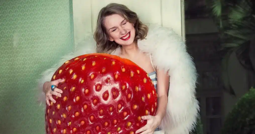 Frau umarmt riesige Erdbeere